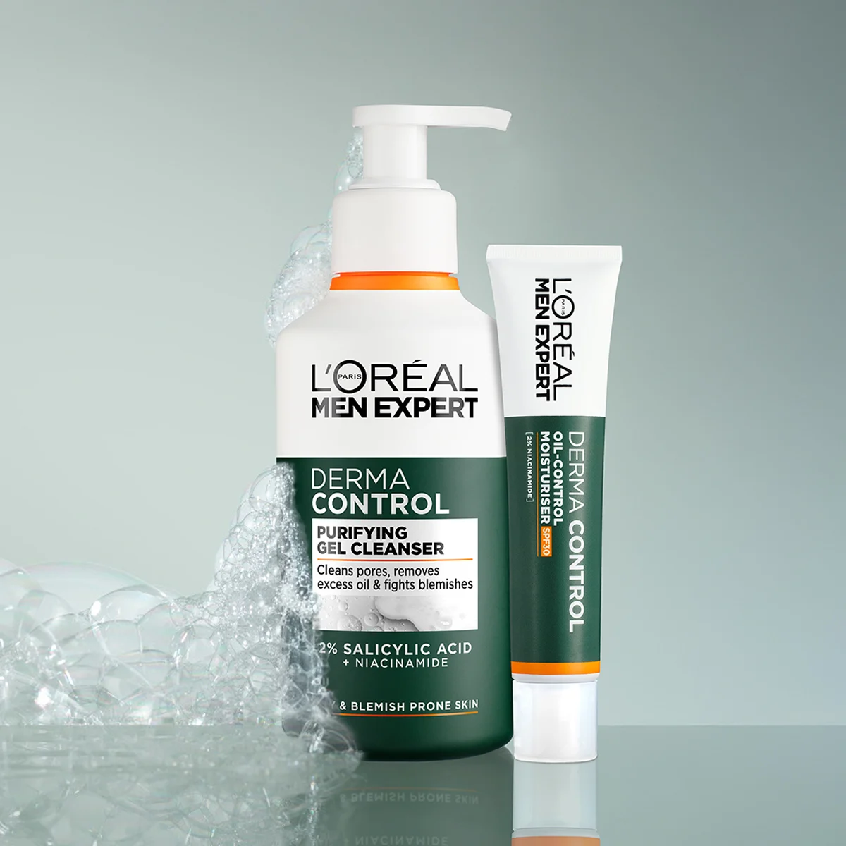 Kaksi L'Oréal Men Expert -tuotetta vierekkäin kiiltävällä pinnalla. Pumppupullo puhdistusgeeliä ja tuubi kosteusvoidetta. Vaahdot ympäröivät pulloa.