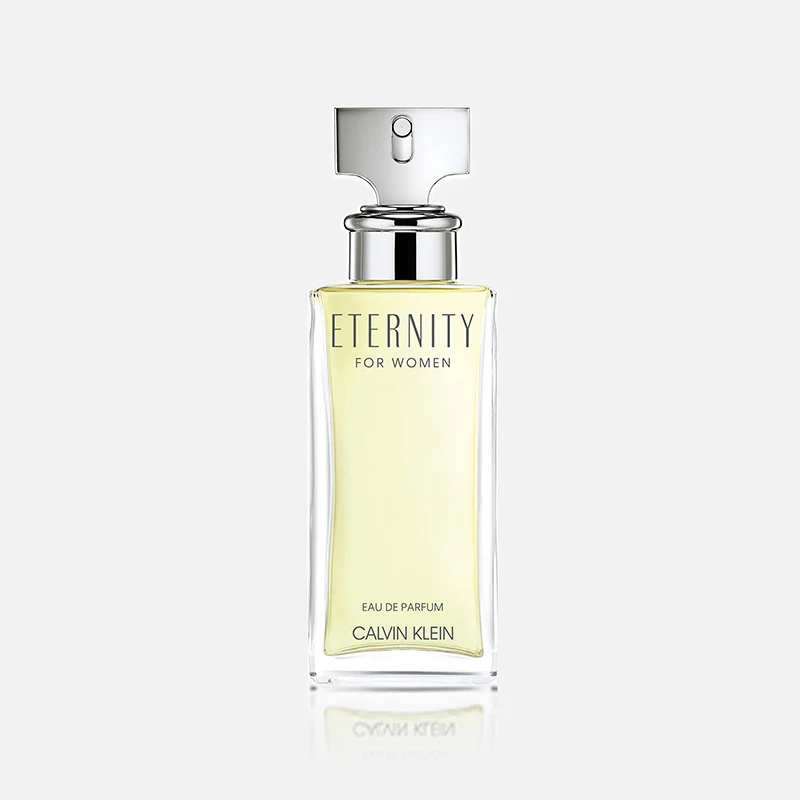Transparent parfymflaska med ljusgul vätska från Calvin Klein med silverfärgad spraykork och texten "ETERNITY FOR WOMEN", "EAU DE PARFUM" och "CALVIN KLEIN".
