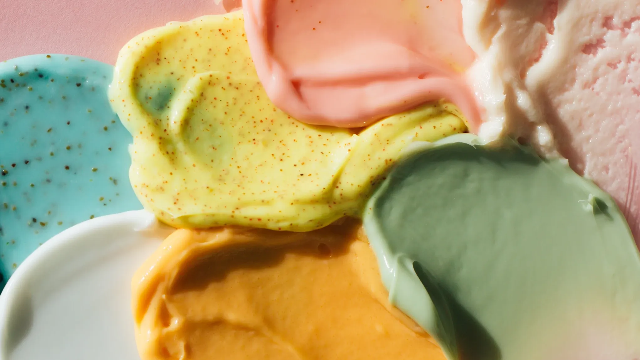 Fargerike hudpleieprodukter smurt ut på en overflate.