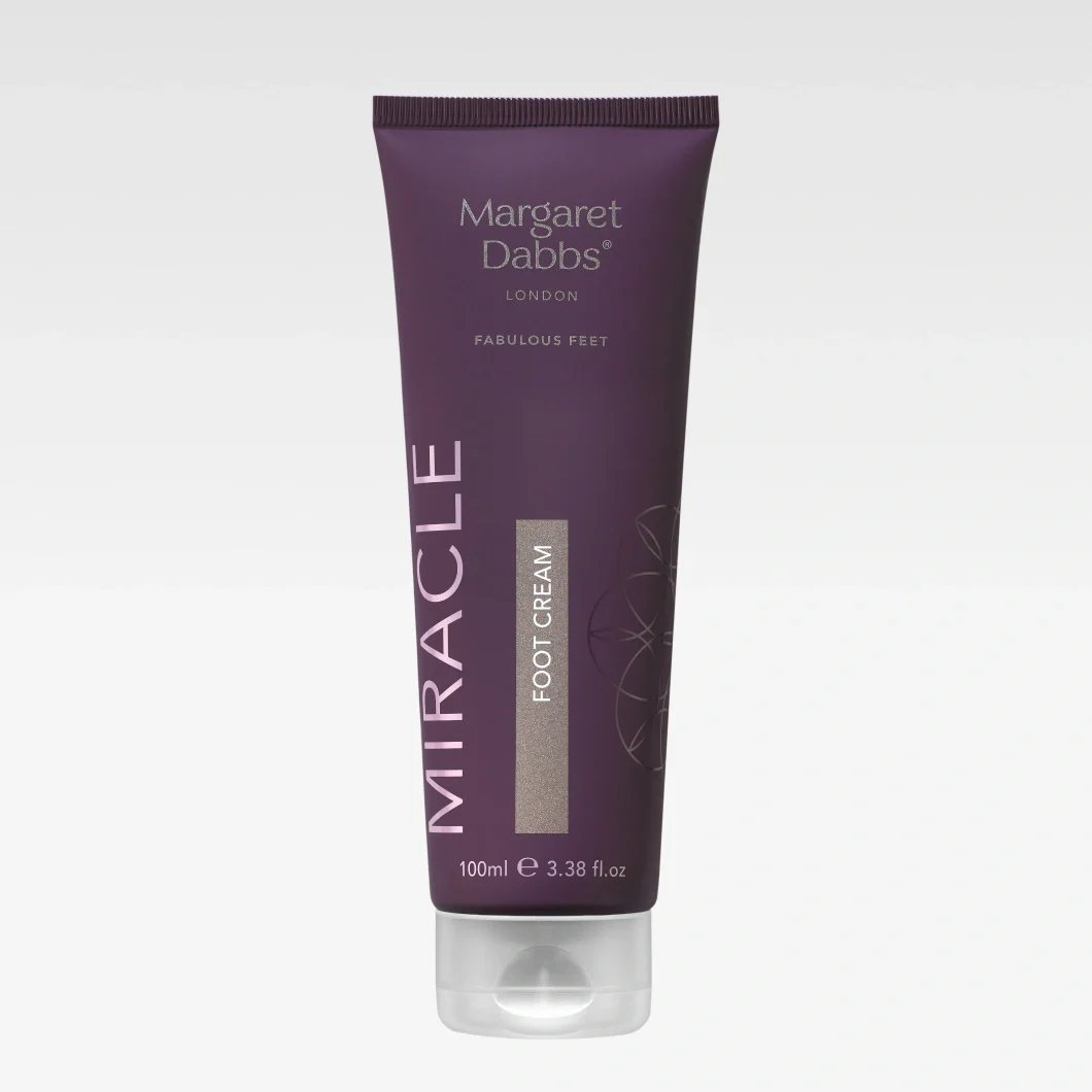 Violetti Margaret Dabbs London Fabulous Feet MIRACLE FOOT CREAM -jalkavoideputkilo. Pakkauksessa näkyvät hopeanväriset tekstit “FOOT CREAM”, “100ml e 3.38 fl.oz” sekä koristeellinen kuvio vaaleanharmaalla taustalla.