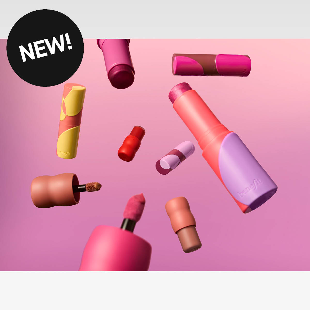 Flere Benefit-sminkeprodukter i ulike farger svever mot rosa bakgrunn. I øvre hjørne vises en svart sirkel med teksten «NEW!».