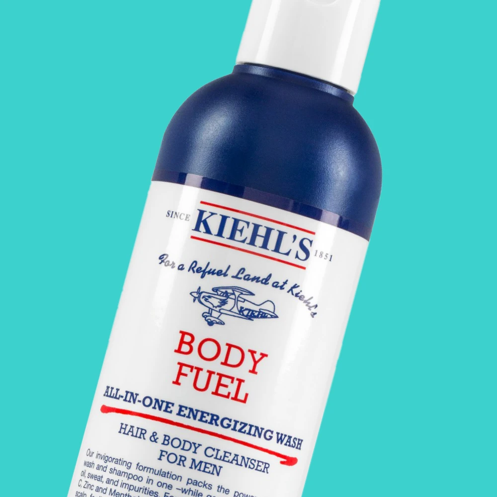 Kuva, joka näyttää valkoinen pullo Kiehl's Body Fuel All-In-One Energizing Wash. Tausta on turkoosi.