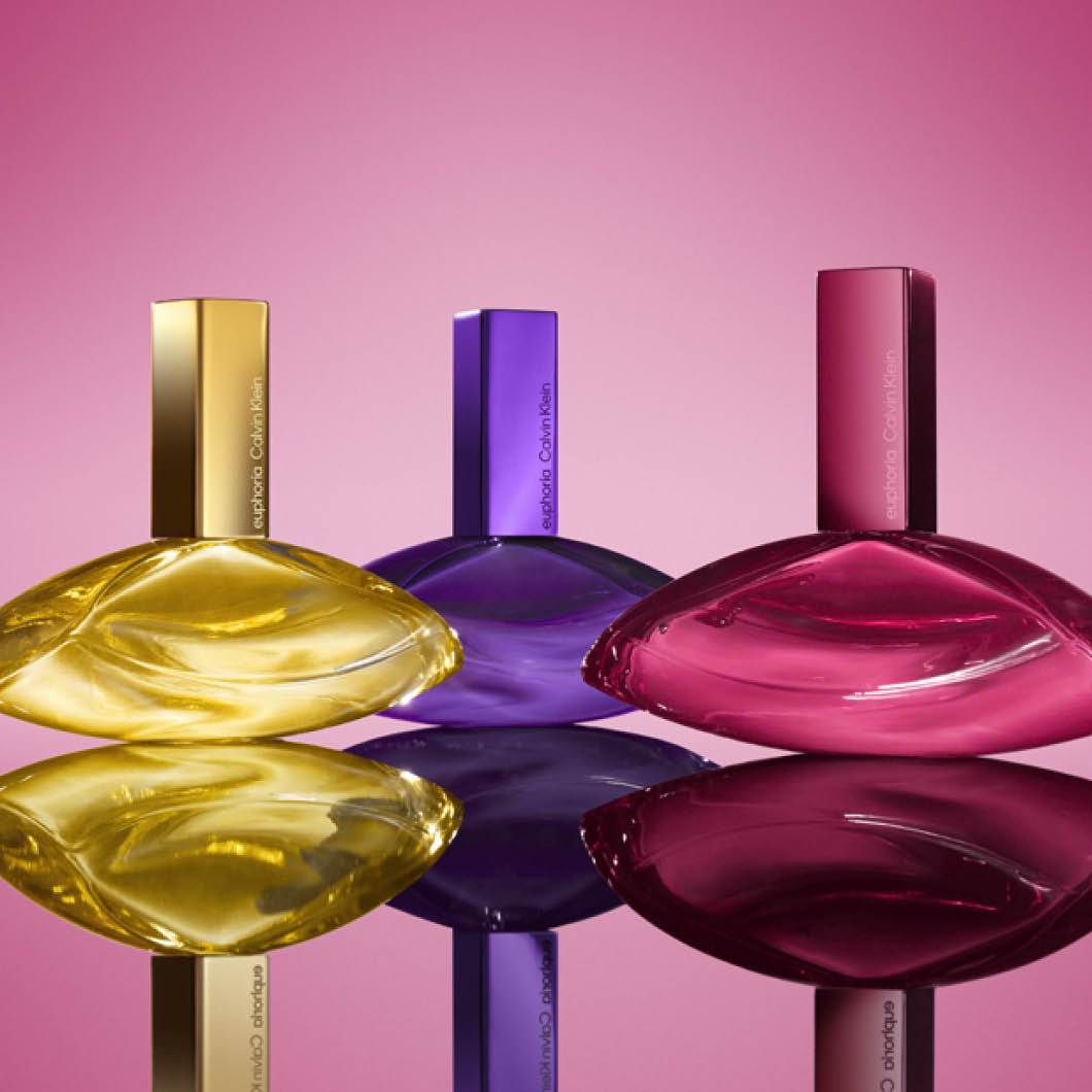 Tre Calvin Klein parfymeflasker i ulike farger på rosa bakgrunn.