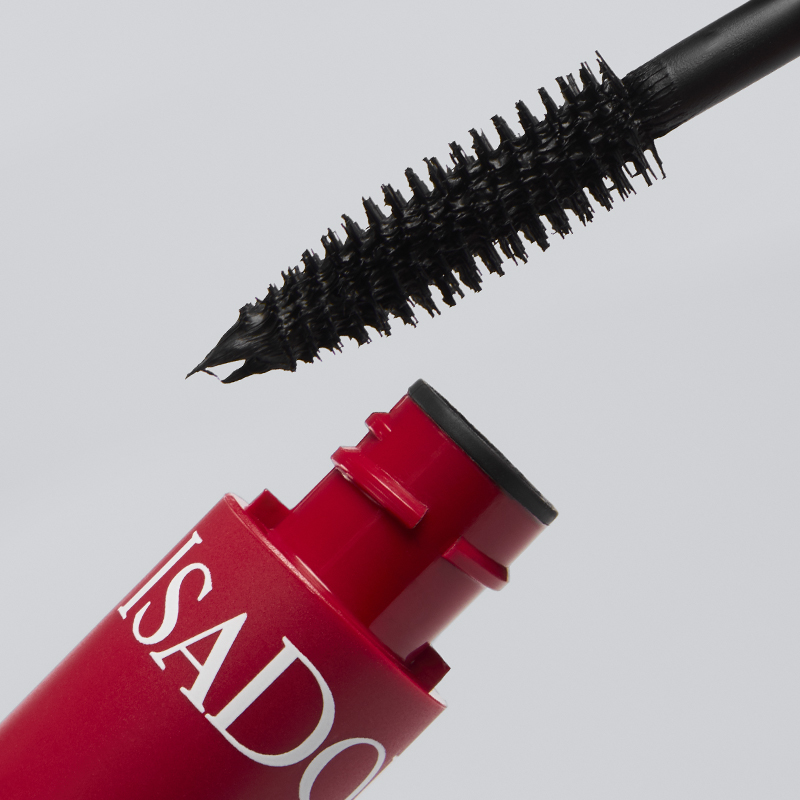 Närbild av IsaDora mascara med röd hylsa och svart borste med synlig produkt på borsten mot ljus bakgrund. Texten ISADORA syns på förpackningen.