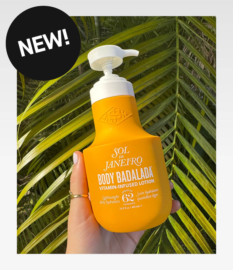 Hand håller Body Badalada flaska från Sol de Janeiro, mot ett grönt palmblad. Svart sticker med texten "First at KICKS!"