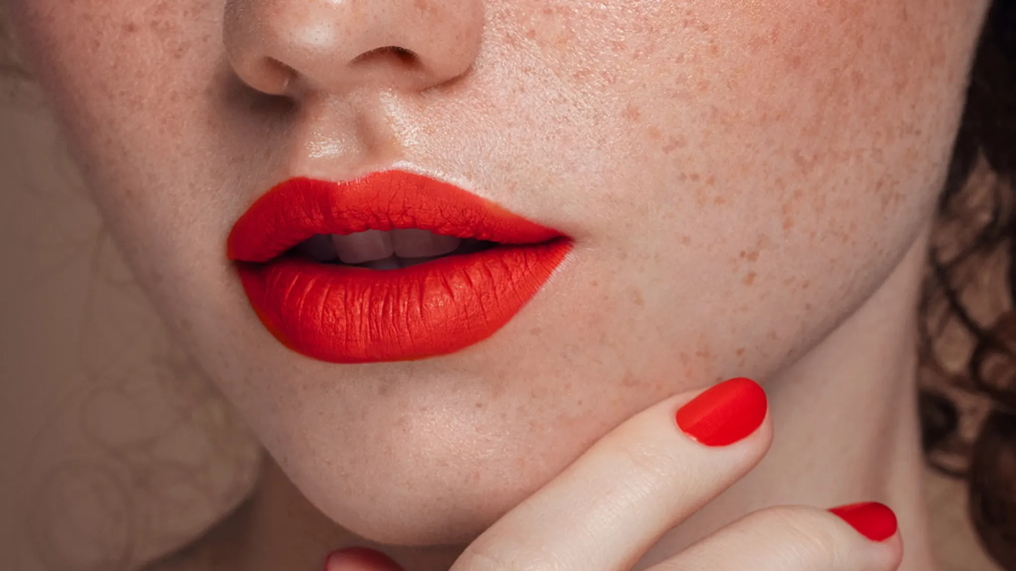 Kvinne med sminke og rød leppestift, med oppsatt hår.