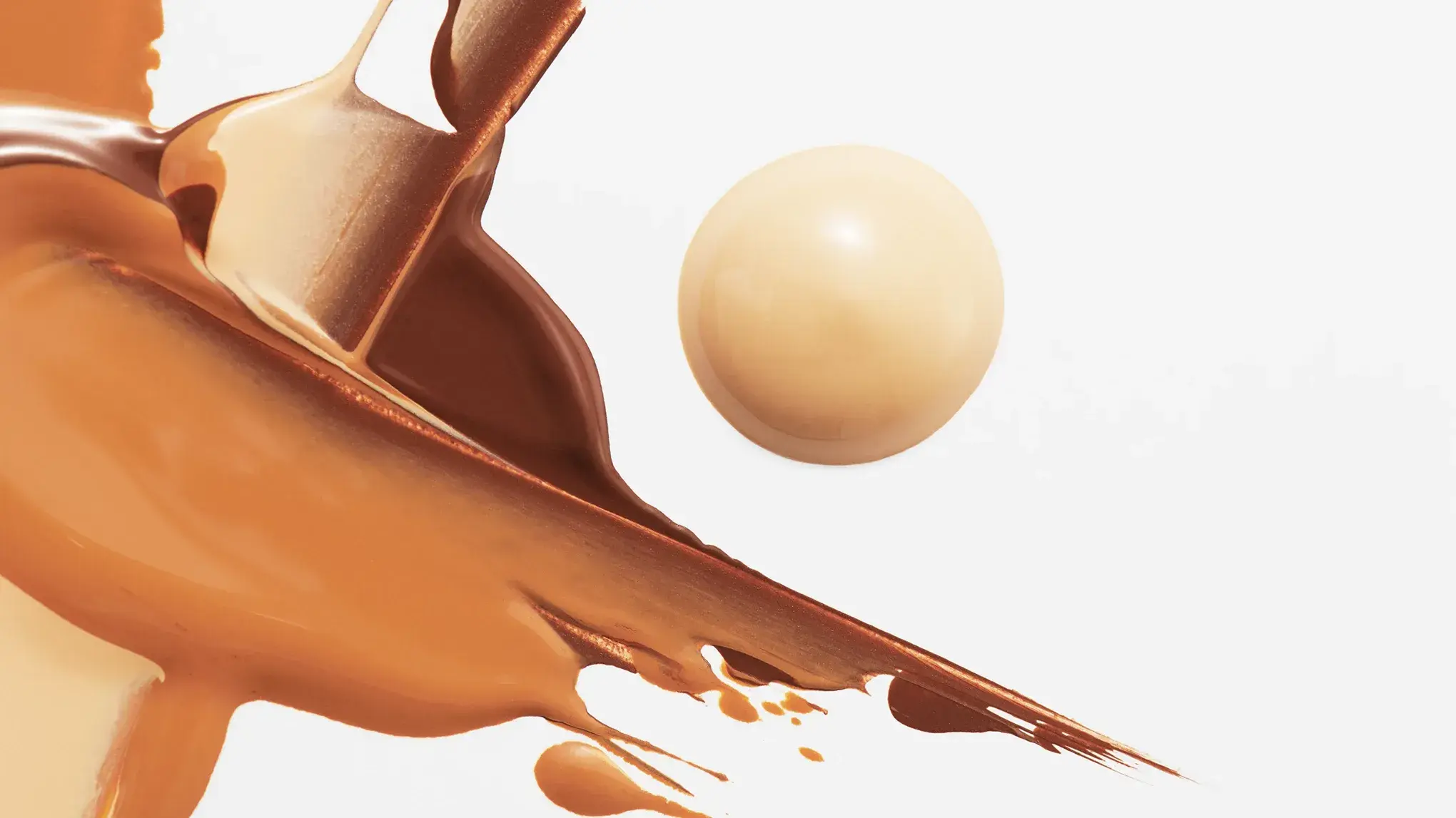 En concealer spredt i et abstrakt mønster i lysebrune toner, med en rund dråpe concealer ved siden – alt mot en hvit bakgrunn.