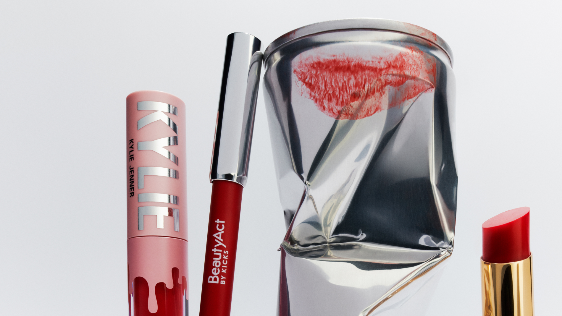 Røde leppeprodukter inkludert leppestift, lipgloss og leppeblyant, ved siden av en knust boks med et leppeavtrykk.