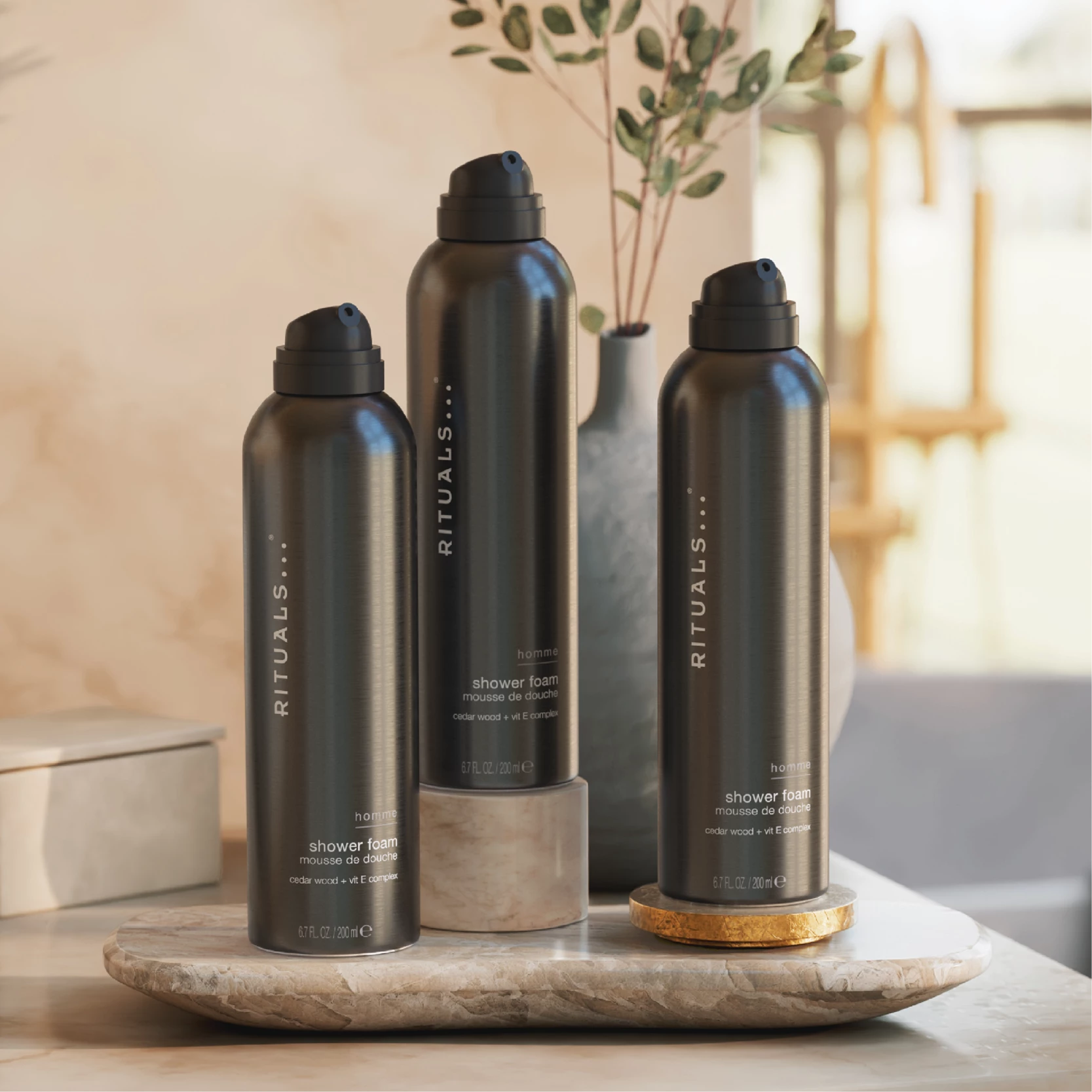 Tre svarte Rituals-produkt for menn står på ein steinplate i eit lyst rom.