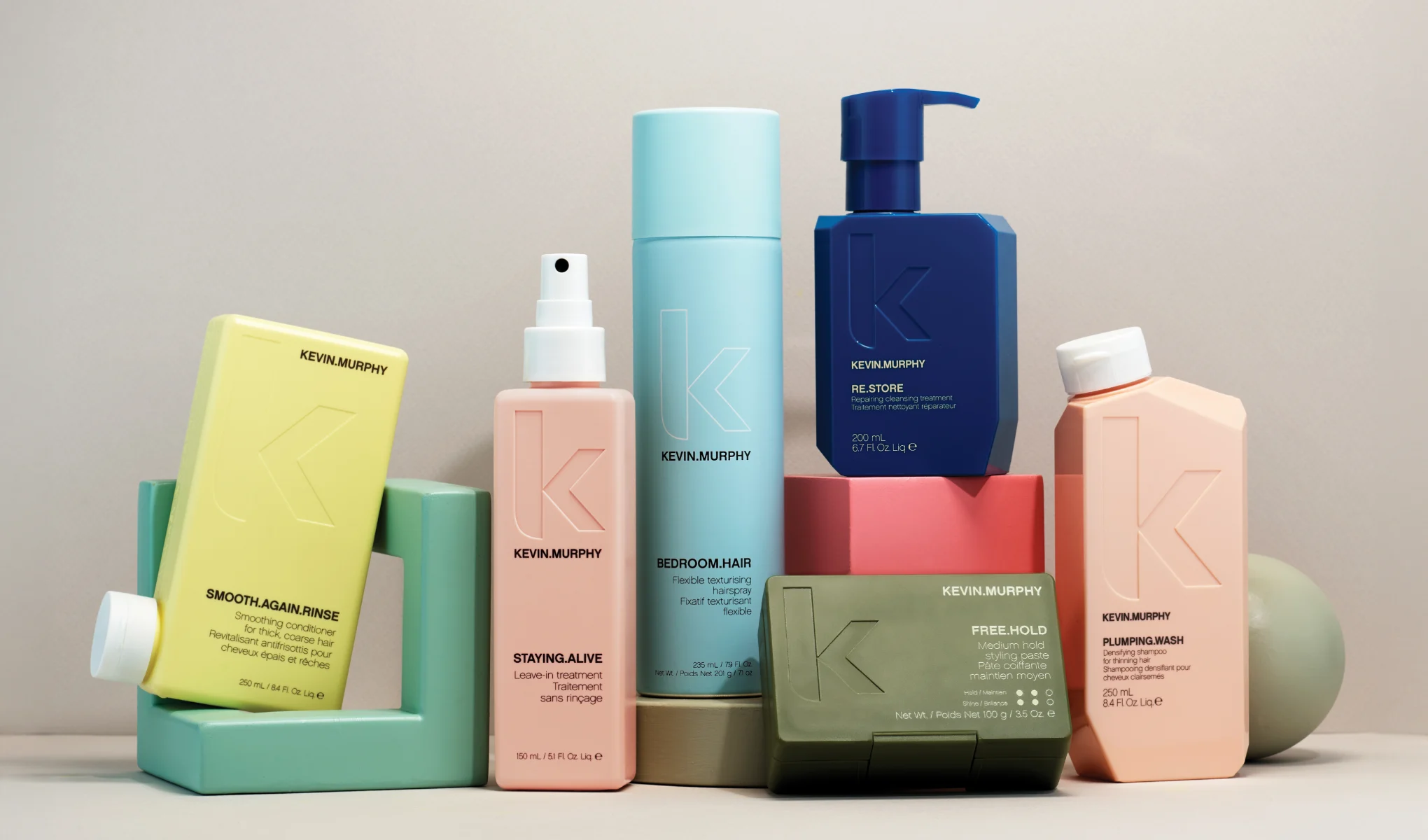 En samling hårvårdsprodukter från Kevin Murphy. Produkterna är arrangerade på en beige bakgrund med geometriska former.