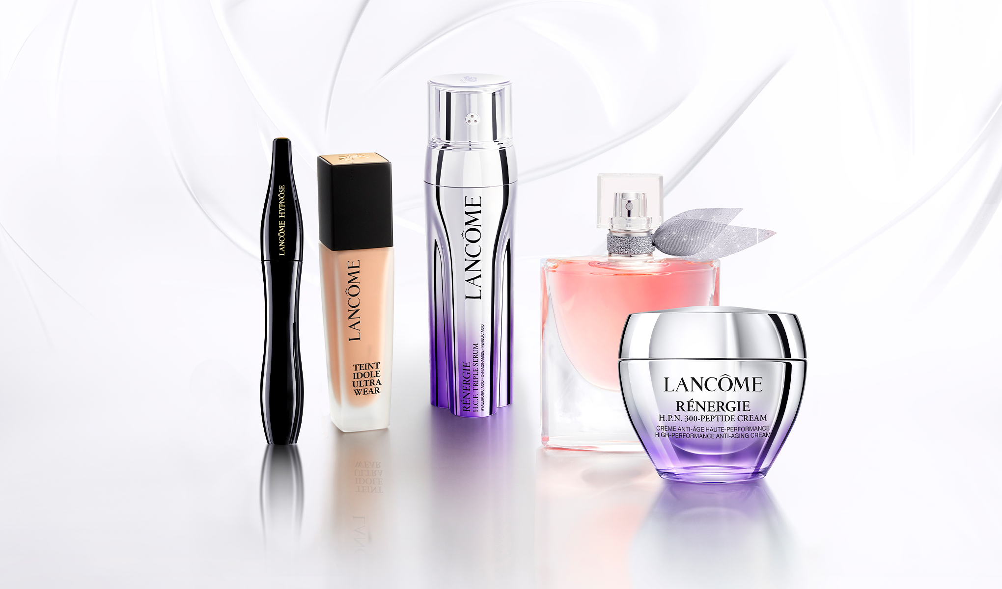 Fem Lancôme-produkter plassert på en hvit flate med en elegant bakgrunn. 