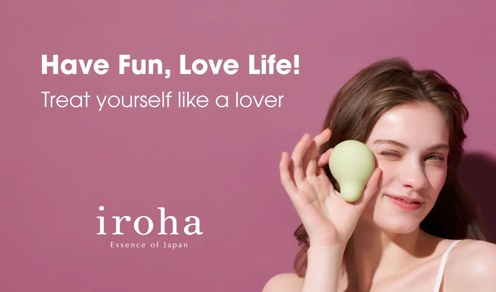 Kampanjebilde mot rosa bakgrunn med teksten “Have Fun, Love Life!” og “Treat yourself like a lover”. En person holder opp et grønt beautyprodukt ved ansiktet. Synlig tekst inkluderer “iroha Essence of Japan”.
