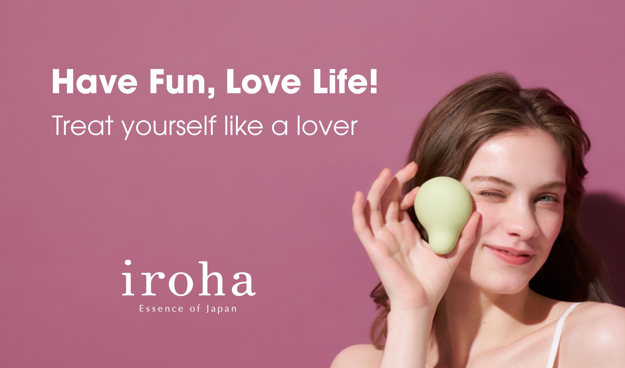 Kampanjbild mot rosa bakgrund med texten “Have Fun, Love Life!” och “Treat yourself like a lover”. En person håller upp en grön beautyprodukt vid ansiktet. Synlig text inkluderar “iroha Essence of Japan”.