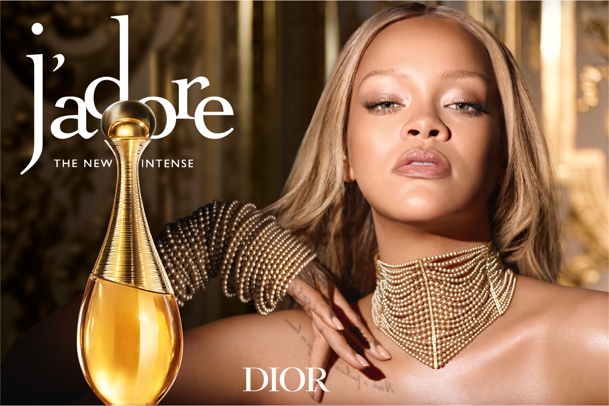 Dior J’adore -hajuvesipullo yhdessä henkilön kanssa, jolla on kullanvärinen koru, sekä tekstit “j’adore”, “DEN NYA INTENSIVA” ja “DIOR”.