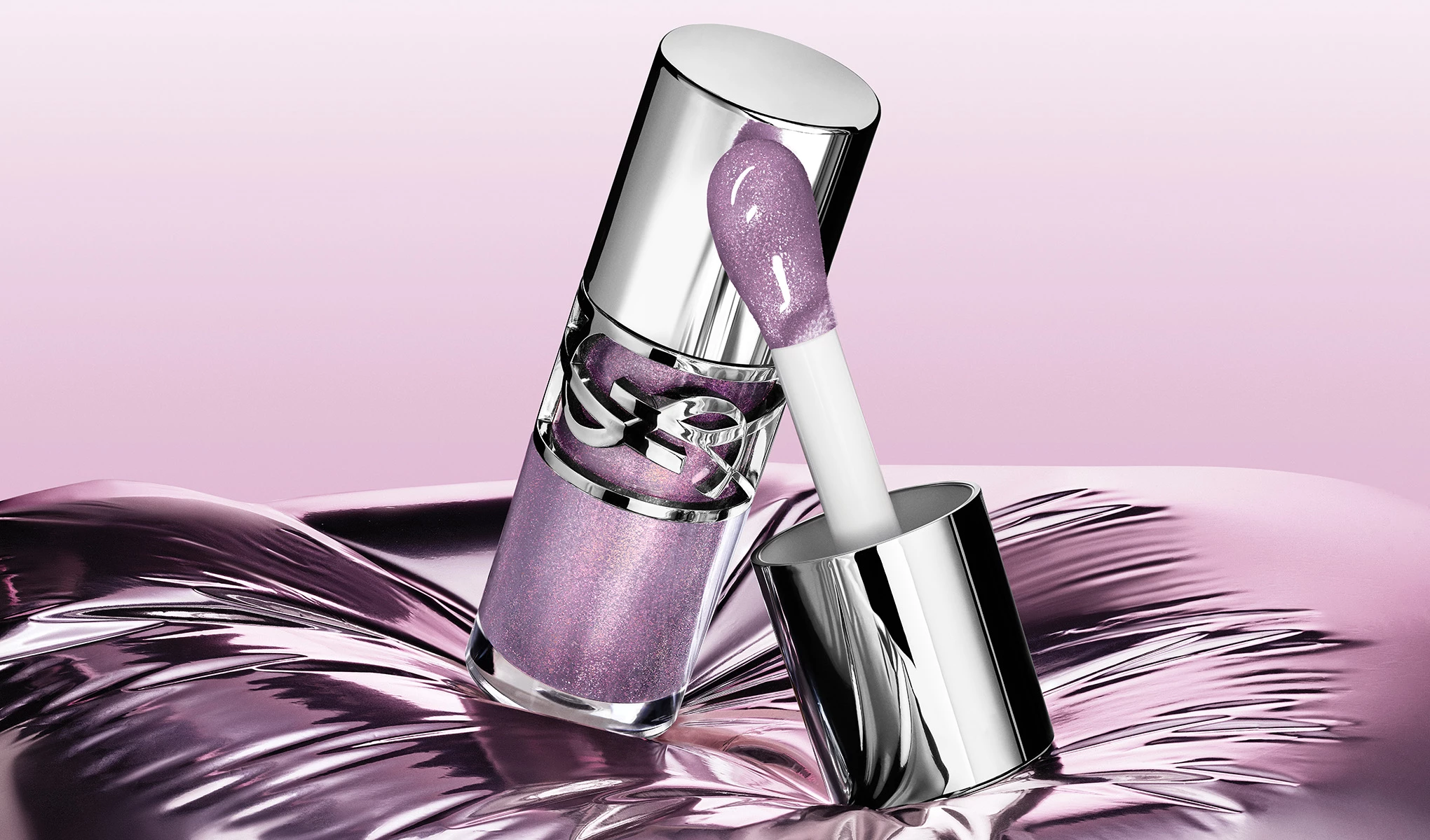 En lilla lipgloss med skinnende sølvdetaljer og applikator er plassert på en metallisk overflate.