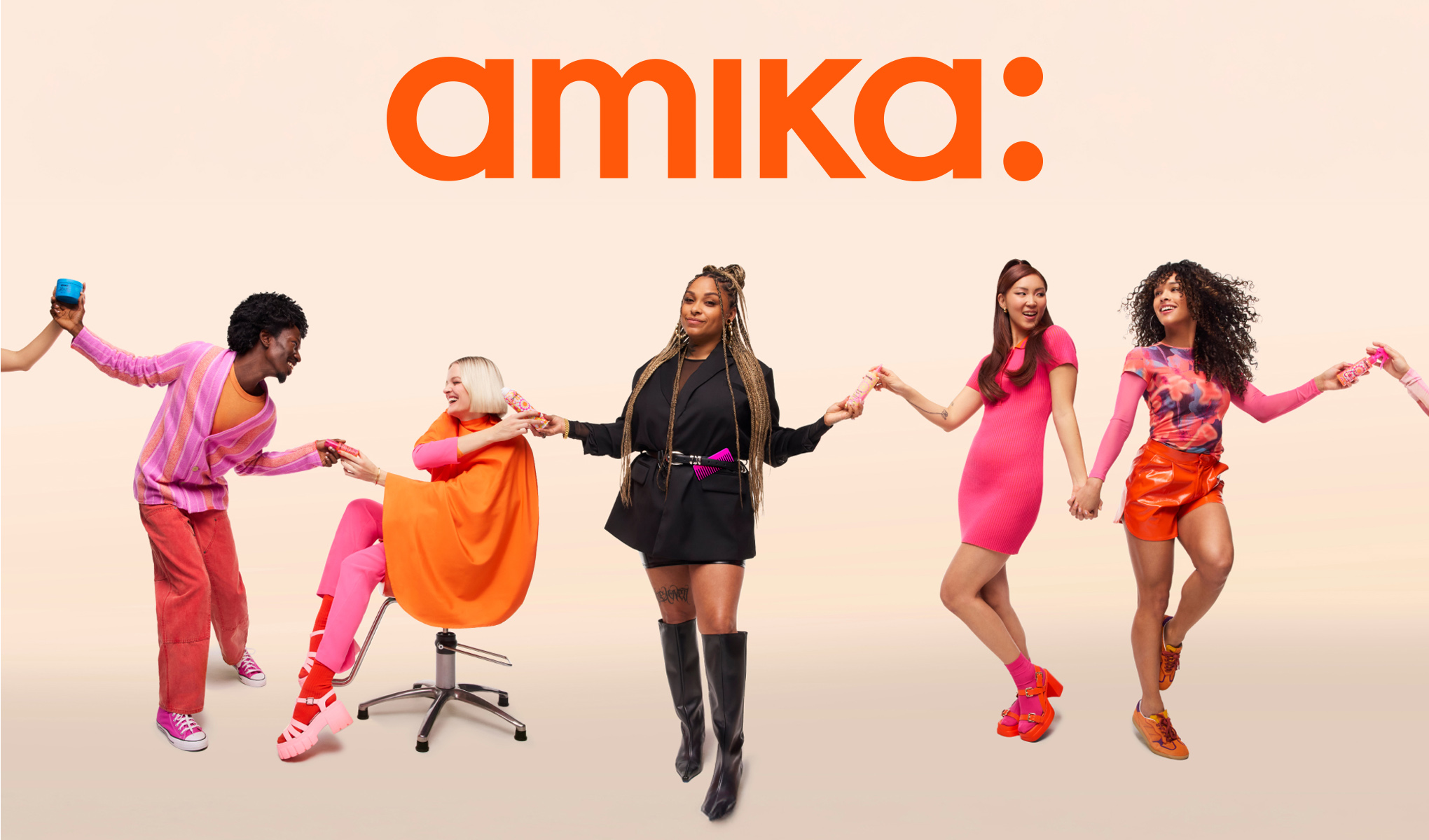 Fem personer står på rad och håller varandra i händerna. Bakom dem syns texten "amika:" i orange färg.