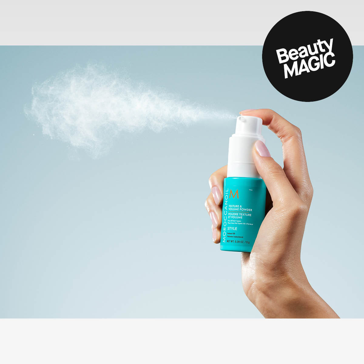 En hånd som sprayer Moroccanoil hårprodukt mot lys blå bakgrunn, med teksten «Beauty MAGIC».
