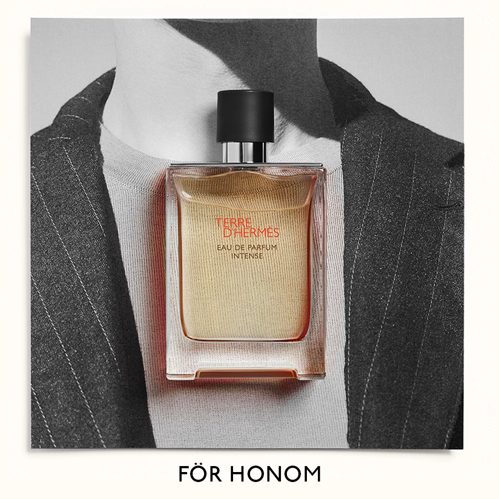 Parfymflaska från Hermès, Terre d'Hermès Eau de Parfum Intense, placerad framför en svartvit bild av en man i kostym. Texten "FÖR HONOM" syns längst ner.