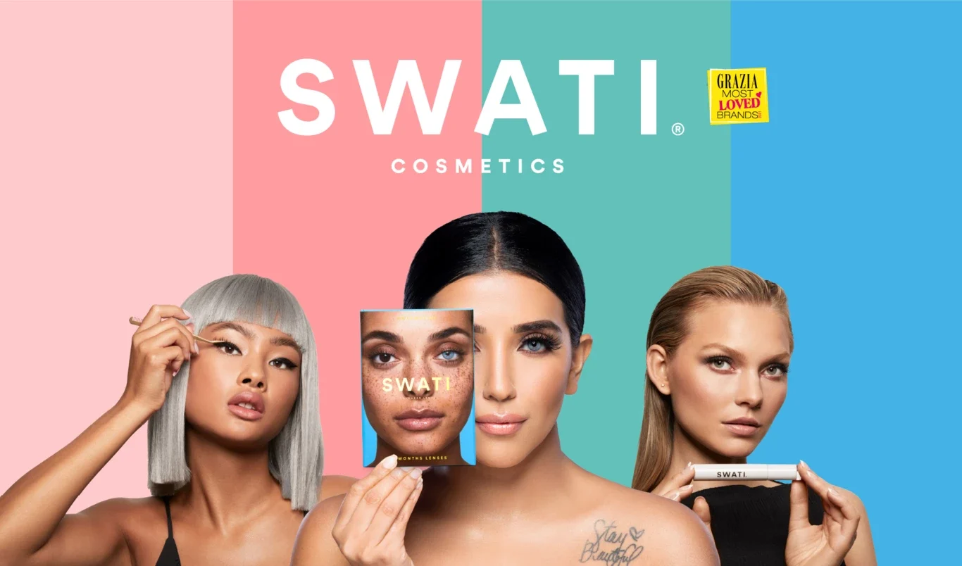 Tre kvinnor med olika hudtoner och hårfärger håller upp produkter från SWATI Cosmetics framför sina ansikten. Bakgrunden är delad i tre färger: rosa, turkos och blå. Texten "SWATI COSMETICS" är placerad ovanför kvinnorna, och en gul etikett med texten "Grazia Most Loved Brands" syns i det blå fältet. Kvinnorna är klädda i svarta toppar.