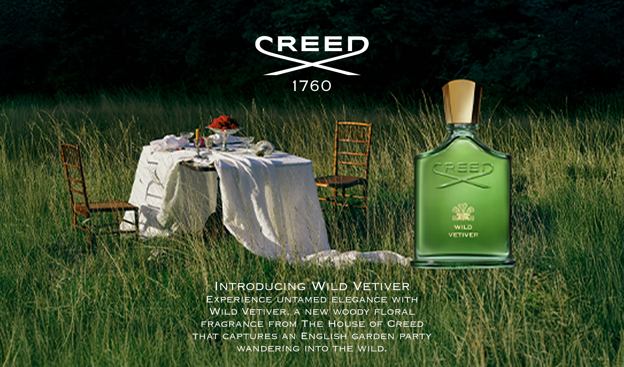 Creed Wild Vetiver parfymflaska i grön glasflaska med guldkork och texten “CREED”, “WILD VETIVER” samt logotypen “CREED 1760”. I bakgrunden syns ett bord dukat med vit duk och stolar i högt gräs, tillsammans med texten “INTRODUCING WILD VETIVER Experience untamed elegance with Wild Vetiver, a new woody floral fragrance from The House of Creed that captures an English garden party wandering into the wild.”