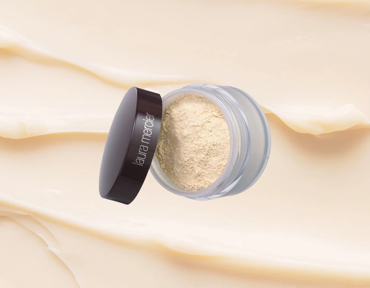 Laura Mercierin Loose Setting Powder Translucent ylhäältä kuvattuna, beigeä taustaa vasten, jossa on laskoksia.