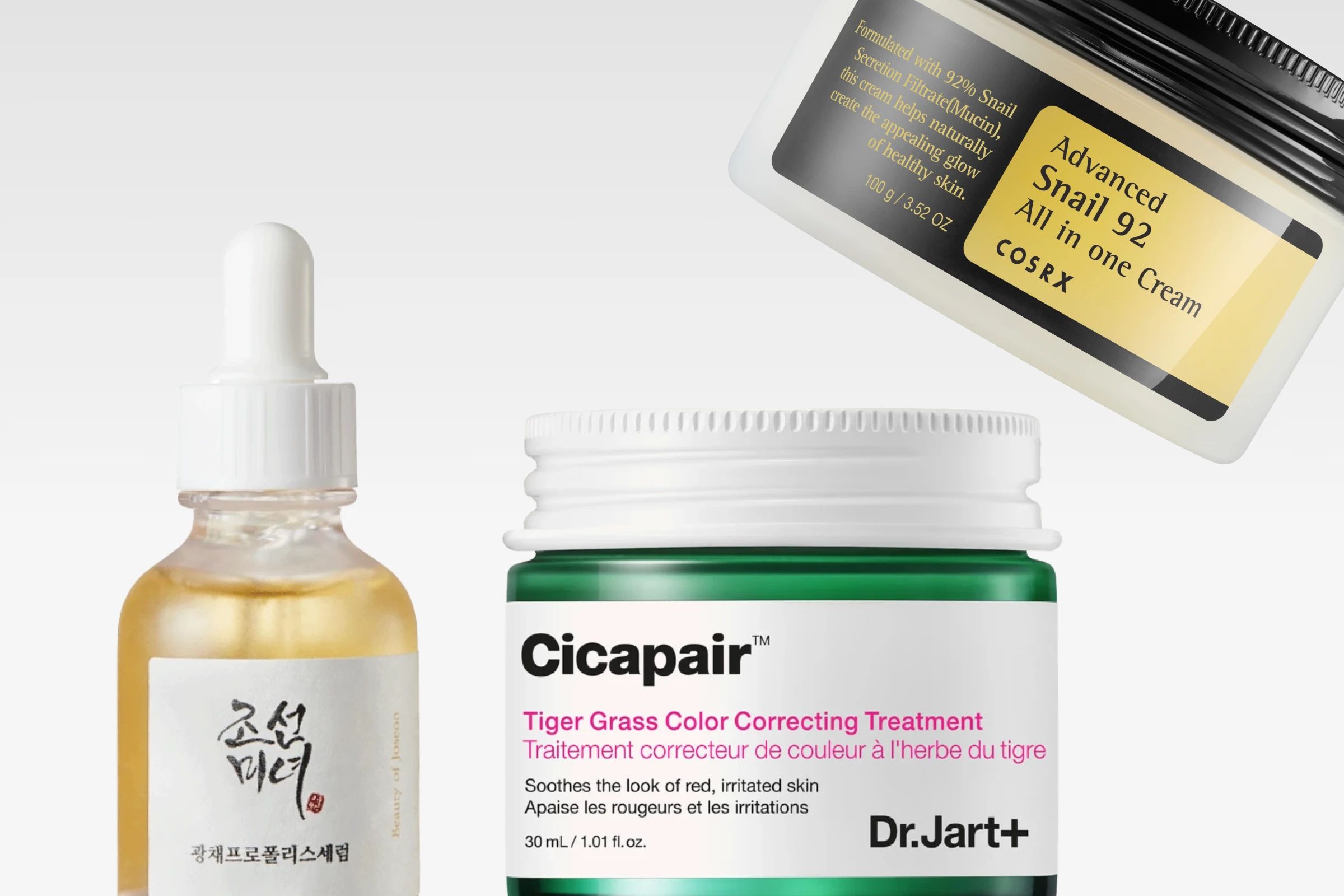 Tre hudpleieprodukter plassert ved siden av hverandre: krukke fra Dr.Jart+, glassflaske med pipette og krukke fra COSRX, mot lys bakgrunn.