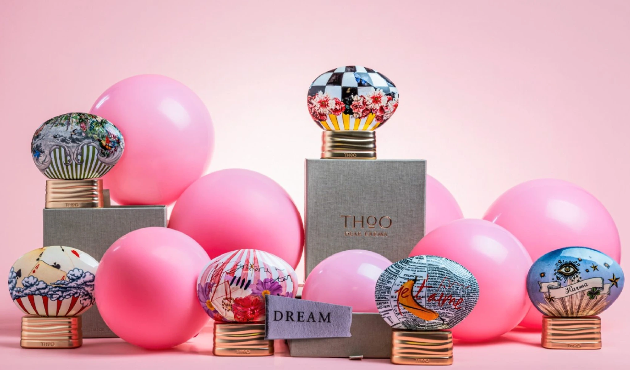 Flere THOO-parfymeflasker med dekorative korker arrangert blant rosa kuler, sammen med esker og teksten “Dream”.