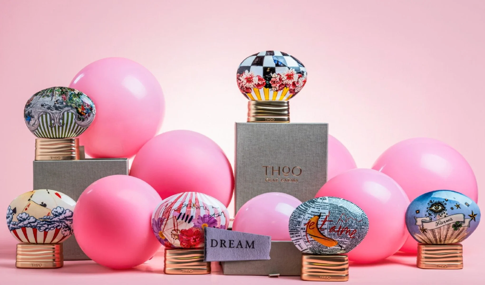 Flere THOO-parfymeflasker med dekorative korker arrangert blant rosa kuler, sammen med esker og teksten “Dream”.