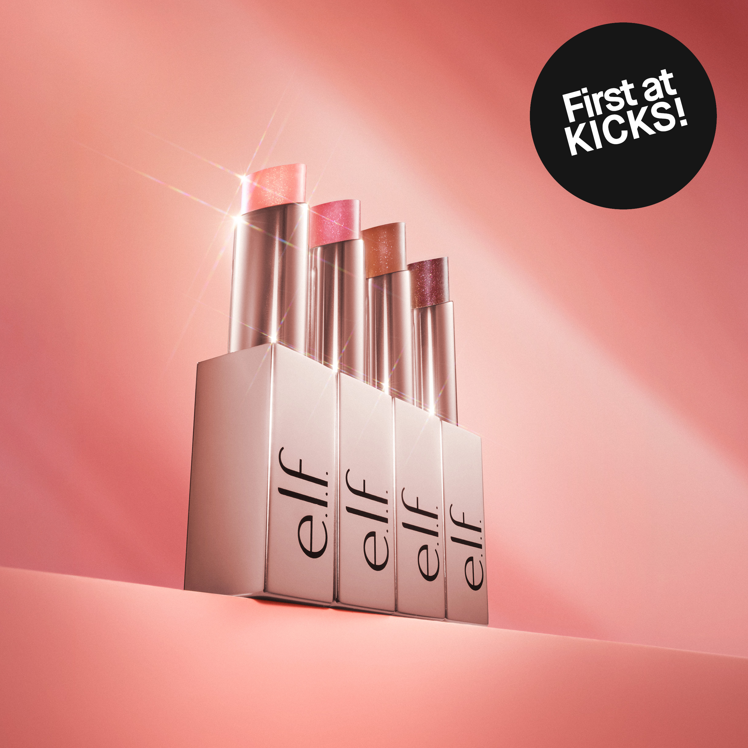 Fyra glittriga läppbalsam från e.l.f. Cosmetics i rosa, persika, brun och bäriga nyanser, med texten 'First at KICKS!'.