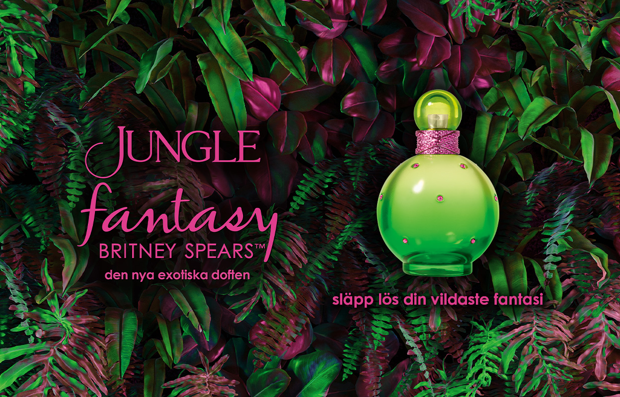 Parfymflaskan "Jungle Fantasy" av Britney Spears, omgiven av frodig grönska och exotiska växter. Texten "Jungle Fantasy Britney Spears™ den nya exotiska doften" och "släpp lös din vildaste fantasi" syns på bilden. Flaskan är grön med rosa detaljer.