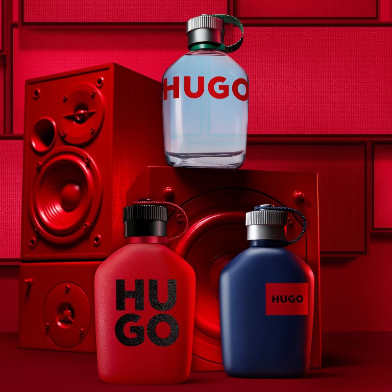 Kolme eriväristä Hugo Boss -hajuvesipulloa, jotka on asetettu punaisen kaiuttimen eteen.