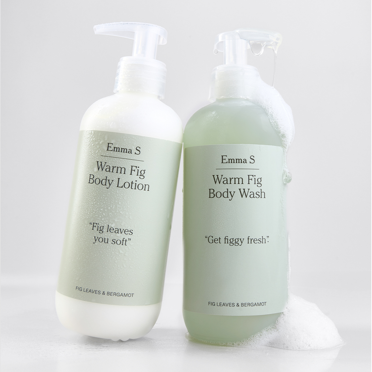 To pumpeflasker fra Emma S med kroppspleie, “Warm Fig Body Lotion” og “Warm Fig Body Wash”, med tekstene “Fig leaves you soft”, “Get figgy fresh” og “Fig Leaves & Bergamot”, hvor én har synlig skum på en lys bakgrunn.