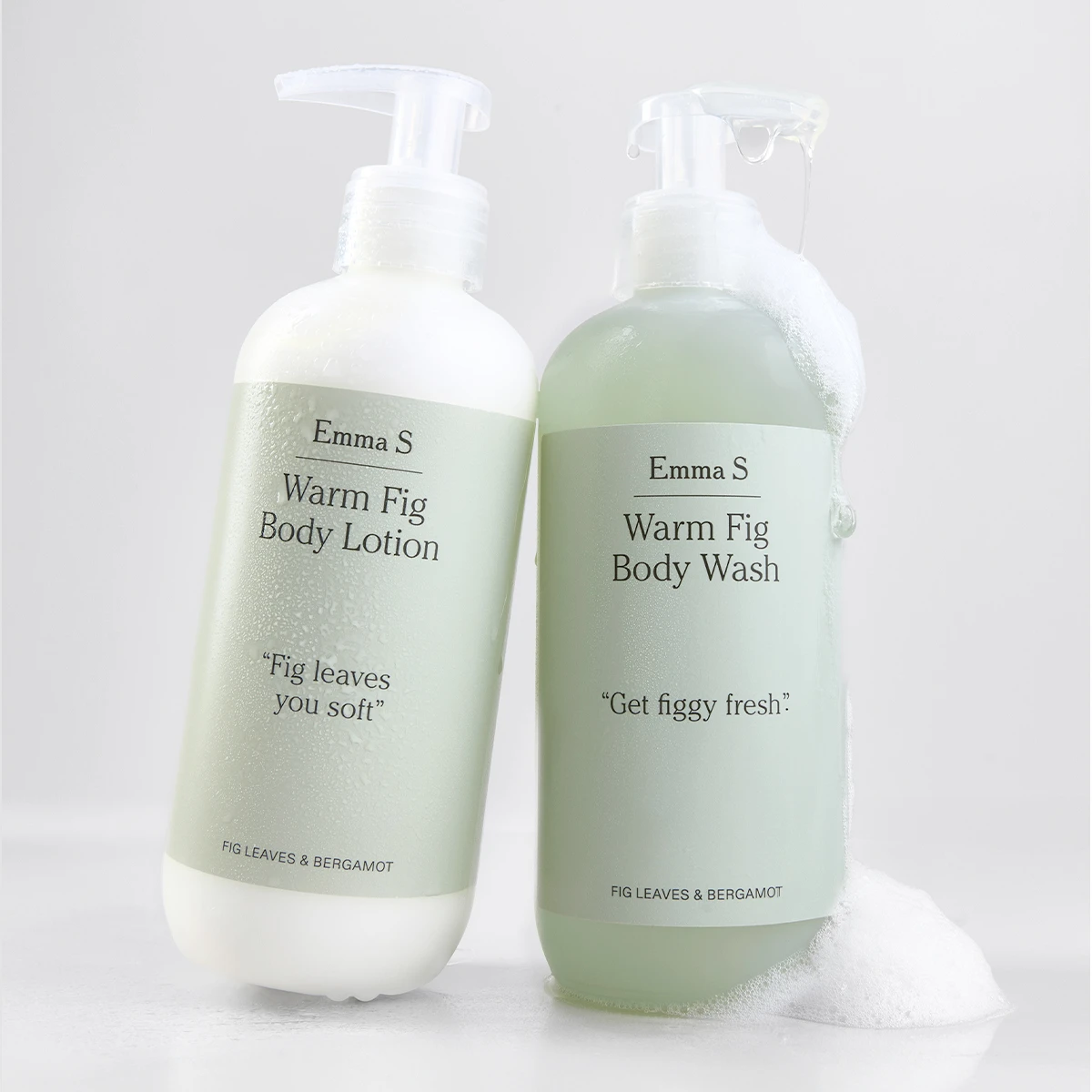 Kaksi Emma S -vartalonhoitopulloa, “Warm Fig Body Lotion” ja “Warm Fig Body Wash”, teksteillä “Fig leaves you soft”, “Get figgy fresh” ja “Fig Leaves & Bergamot”, toisessa näkyy vaahtoa vaaleaa taustaa vasten.