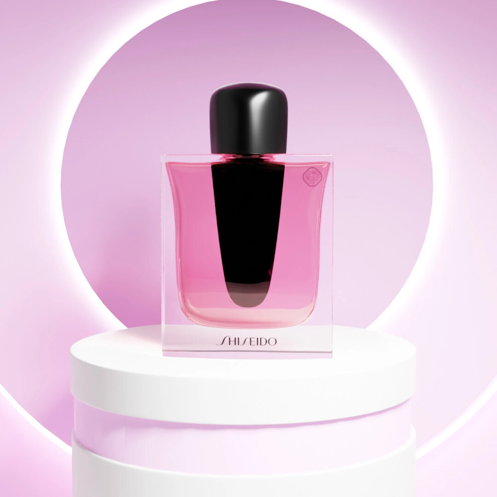 Shiseido parfymflaska med rosa vätska placerad på en piedestal framför en rund ljusring.