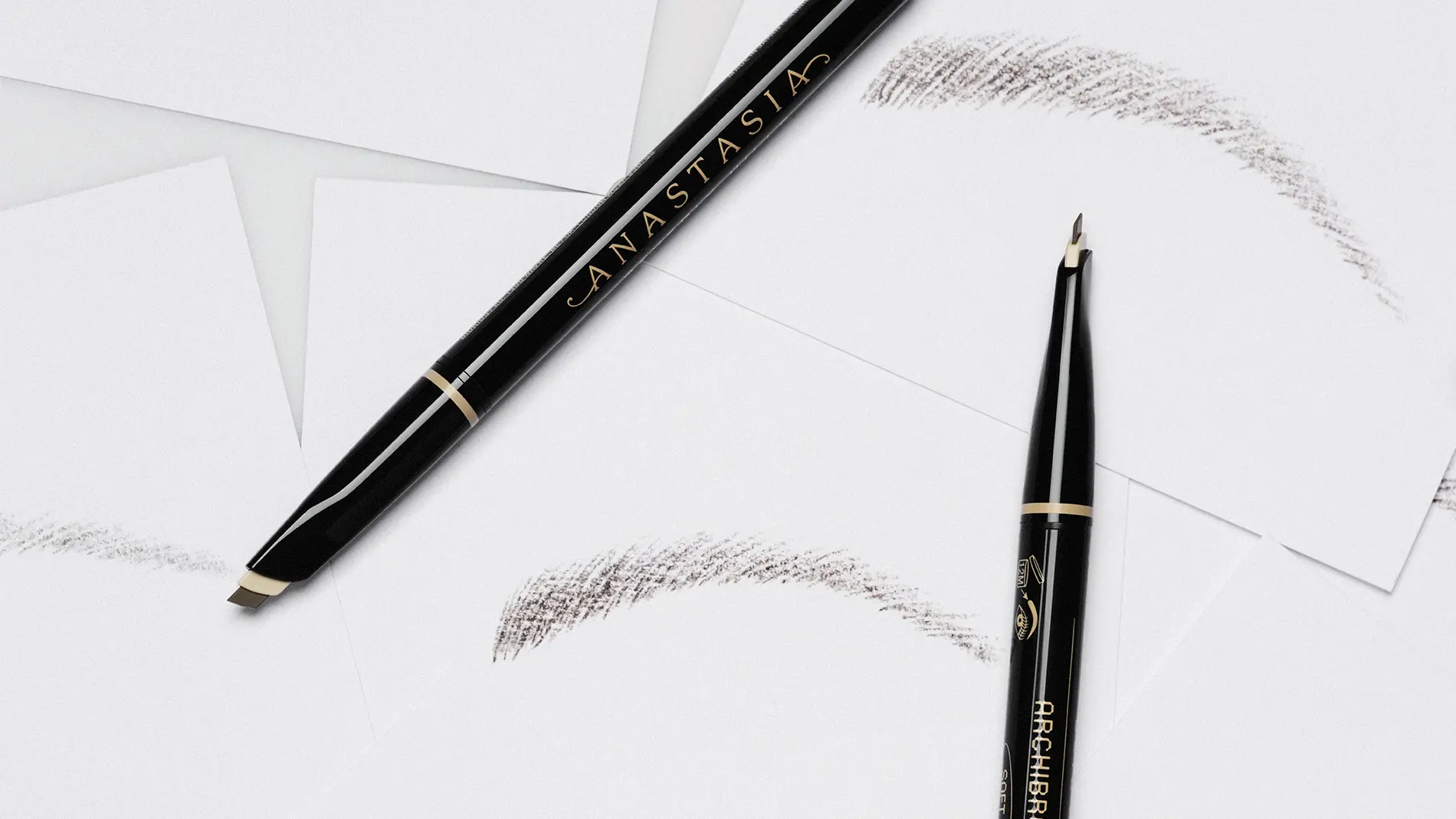 Musta Anastasia Beverly Hills -kulmakynä, jossa teksti "ANASTASIA" ja "BROW WIZ", mukana spoolie-harja ja useita kulmavärin vetoja valkoisella taustalla.