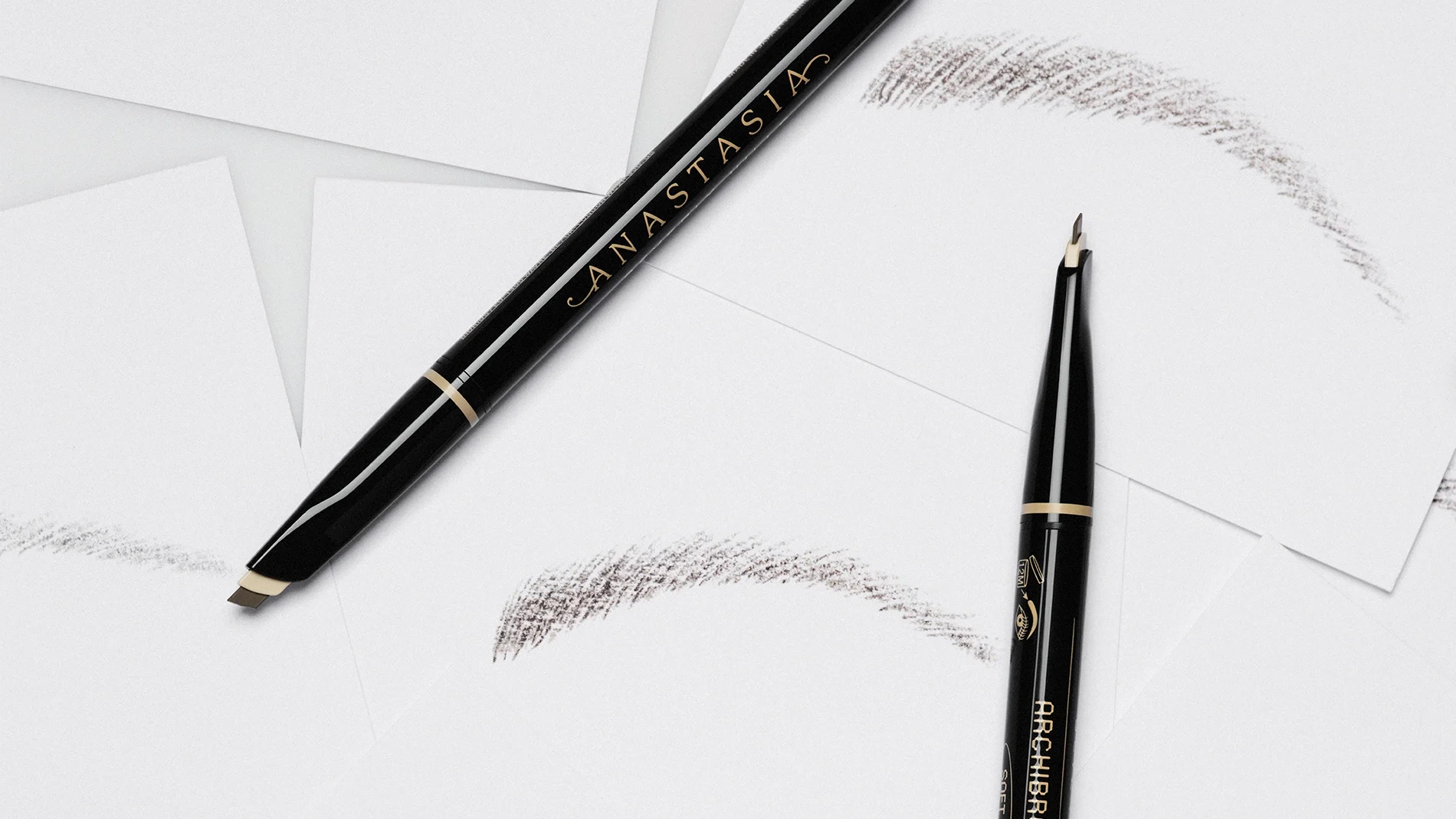 Musta Anastasia Beverly Hills -kulmakynä, jossa teksti "ANASTASIA" ja "BROW WIZ", mukana spoolie-harja ja useita kulmavärin vetoja valkoisella taustalla.