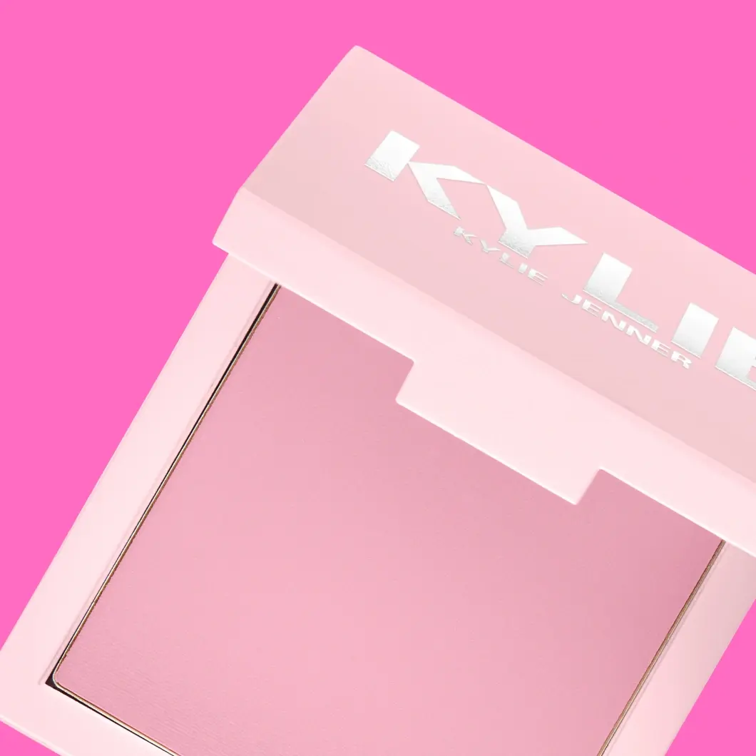 Avoin vaaleanpunainen puuterirasia, jossa 'Kylie Jenner' -logo kannessa ja vaaleanpunainen poskipuna sisällä.