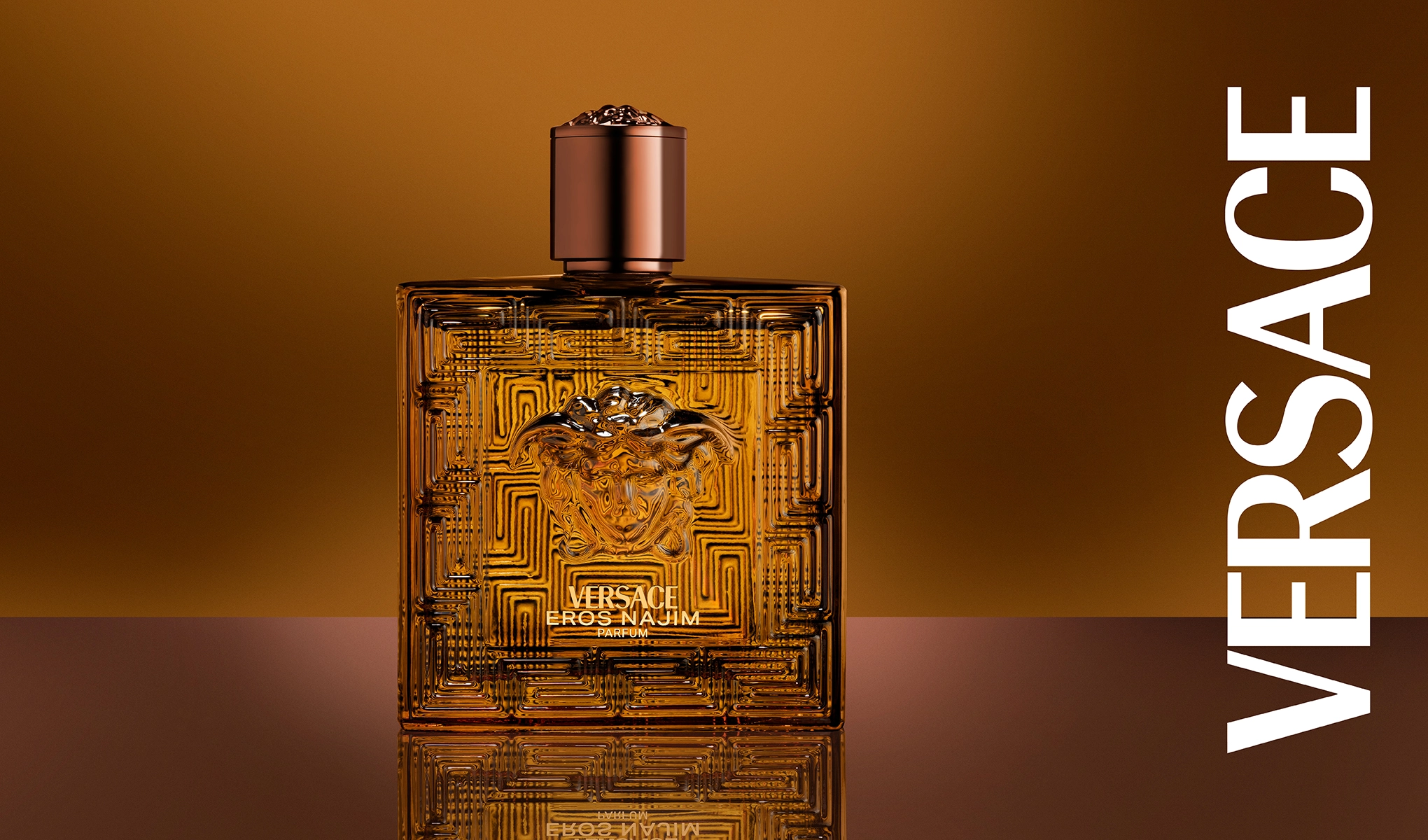 VERSACE EROS NAJIM - Parfymflaska med brun kork. Flaskan står på en blank yta mot en brun bakgrund.