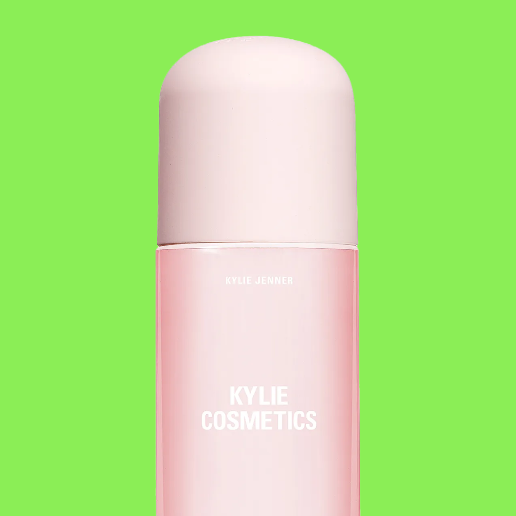 Flaska märkt “KYLIE JENNER KYLIE COSMETICS” i rosa ton mot grön bakgrund.
