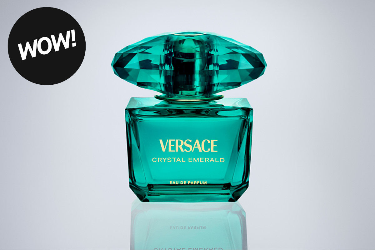 Versace Crystal Emerald Eau De Parfum i turkis glassflaske med fasettslipt kork mot lys bakgrunn. Synlig tekst inkluderer “WOW!”, “VERSACE”, “CRYSTAL EMERALD” og “EAU DE PARFUM”.