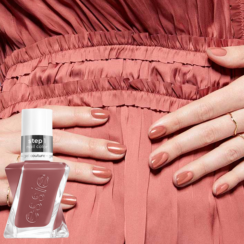 Kaksi kättä, joissa on Essie Gel Couturen vaaleanpunainen kynsilakka, vaaleanpunaista mekkoa vasten. Käsien vasemmalla puolella näkyy pullo samaa vaaleanpunaista kynsilakkaa.
