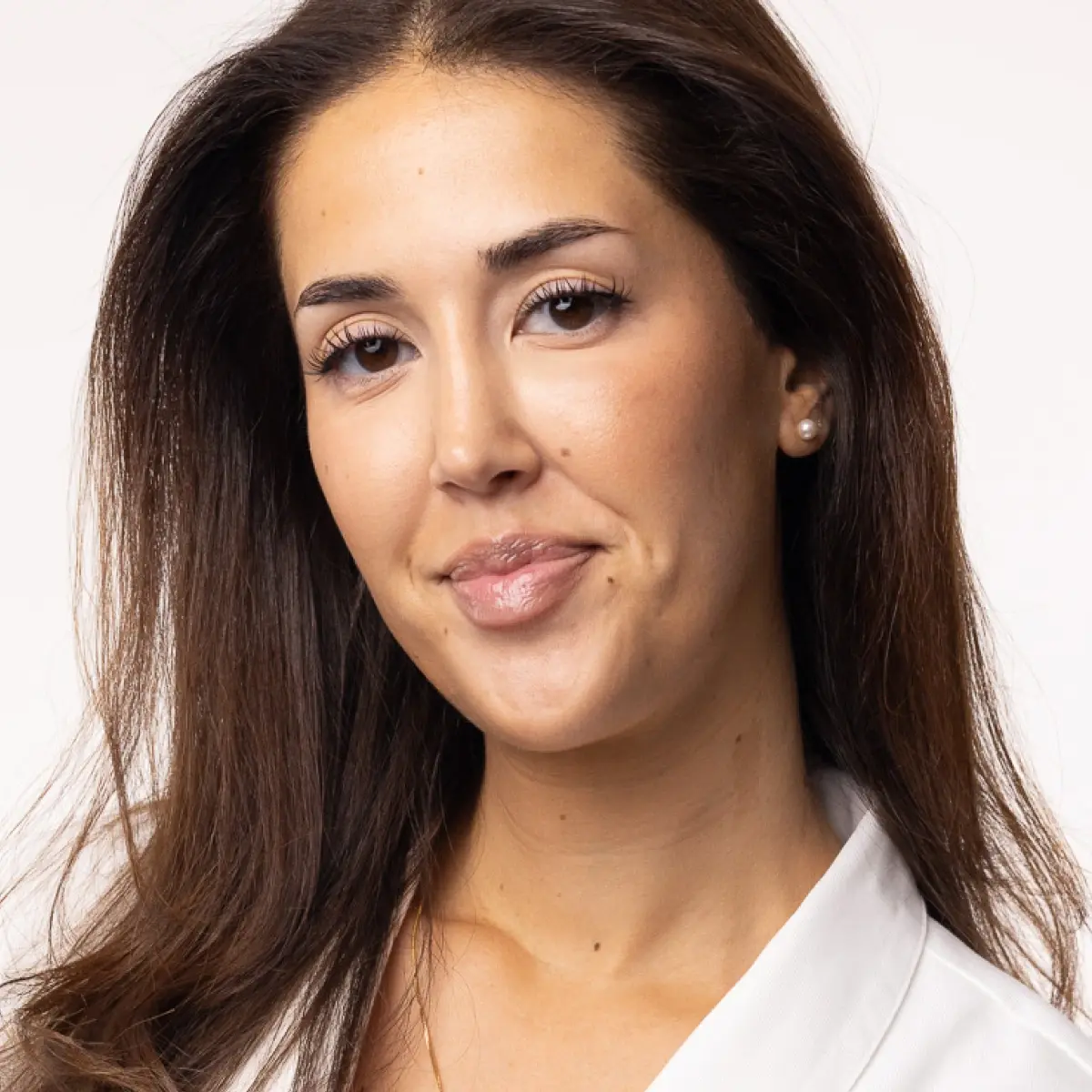 Porträtt av person med naturlig makeup och slät hud, blick riktad mot kameran.