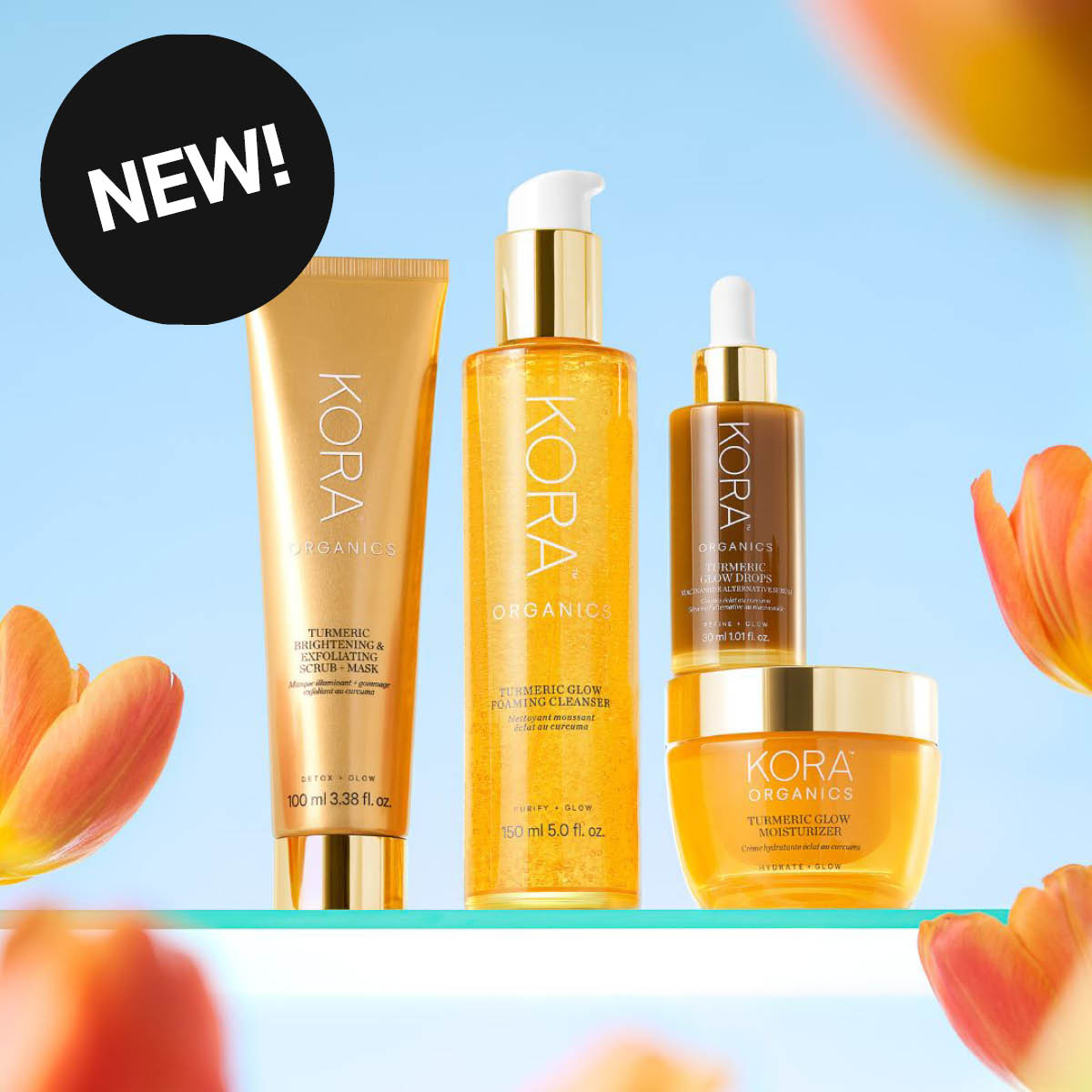 Fire økologiske Turmeric Glow hudpleieprodukter fra KORA Organics av Miranda Kerr. Mot blå bakgrunn med innslag av tulipaner. Klistremerke med teksten NEW