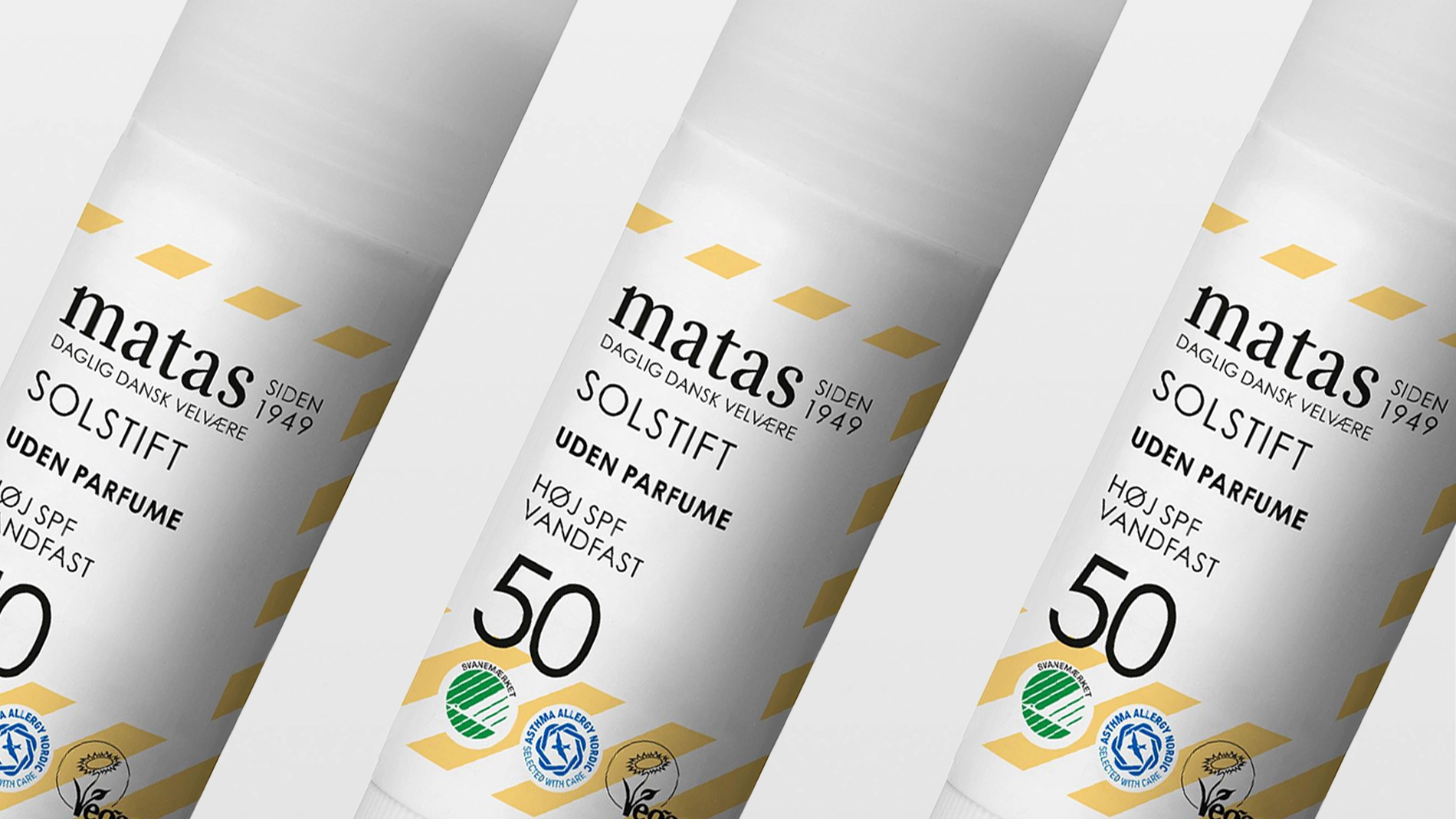 Useita Matas Solstift SPF 50 -puikkoja, joissa tekstit “matas SIDEN 1949”, “SOLSTIFT”, “UDEN PARFUME”, “HØJ SPF”, “VANDFAST” sekä merkinnät kuten Joutsenmerkki ja Asthma Allergy Nordic. Fokus aurinkosuojassa, aurinkosuojapuikossa ja SPF 50 -suojassa valkoisessa pakkauksessa keltaisilla yksityiskohdilla.