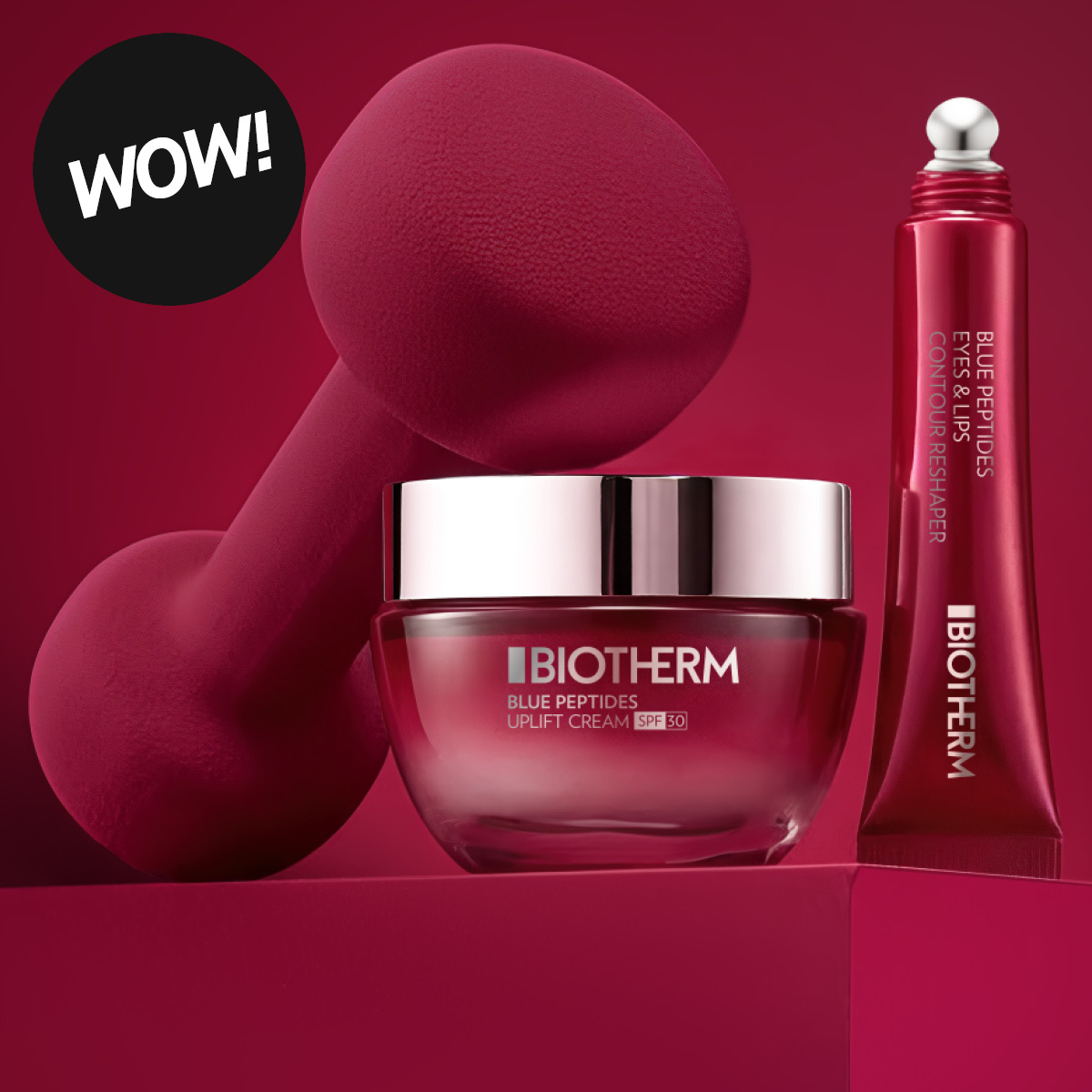 Hudvårdsprodukter från Biotherm med texten “BIOTHERM Blue Peptides Uplift Cream SPF 30” och “Blue Peptides Eyes & Lips Contour Reshaper”. En kräm i burk och en röd tub presenteras mot en röd bakgrund tillsammans med en rund etikett med texten “WOW!”.