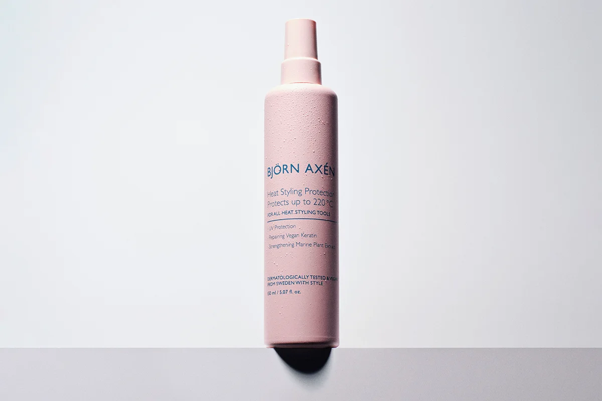 Björn Axén Heat Styling Protection. Produktet kommer i en rosa sprayflaske. Flasken står mot en hvit bakgrunn.