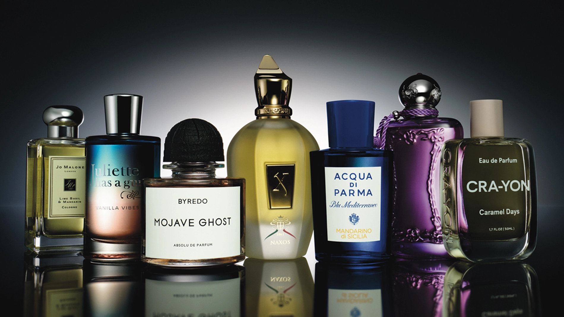 En rad parfymflaskor i olika former och färger, elegant uppställda mot en mörk bakgrund med ljusreflektion.