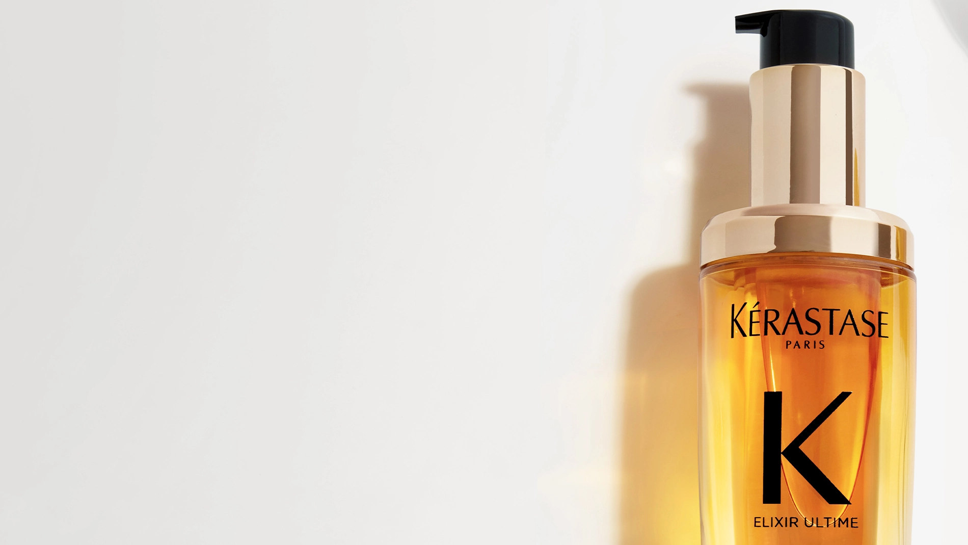 Flaska med Kérastase Elixir Ultime hårolja, med en svart pump och guldiga detaljer.