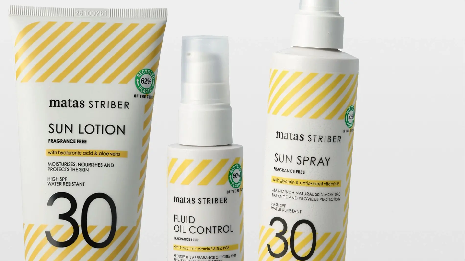 Kolme aurinkosuojatuotetta Matas Striber -sarjasta: tuubi “SUN LOTION”, pumppupullo “FLUID OIL CONTROL” ja suihkepullo “SUN SPRAY”, kaikissa keltaiset vinoraidat ja teksti “FRAGRANCE FREE”. Pakkauksissa näkyy “with hyaluronic acid & aloe vera”, “with glycerin and antioxidant vitamin E”, “HIGH SPF 30”, “WATER RESISTANT” sekä merkinnät “RECYCLED 62% PLASTIC” ja “RECYCLED 50% PLASTIC”.