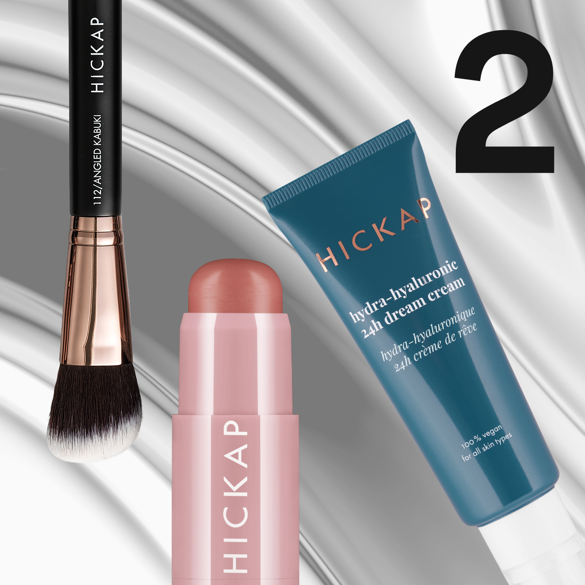 Tre Hickap-produkter mot en metallisk sølvbakgrunn – en børste, en rosa rouge-stick og en blå kremtube.